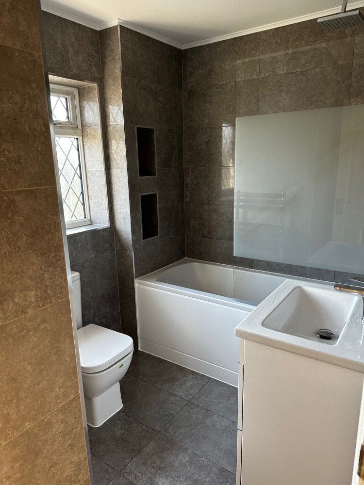 Finished bathroom with stone-effect tiling and recessed shelving